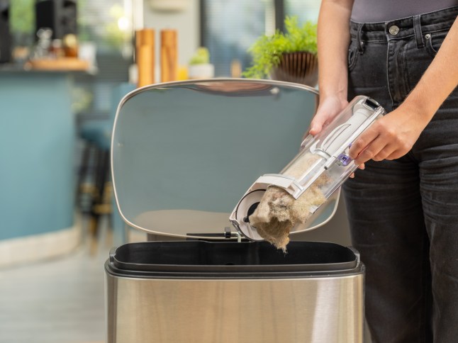 Person emptying AirRAM Platinum Anti Hair Wrap Cordless Vacuum & Speed Cleaning Kit