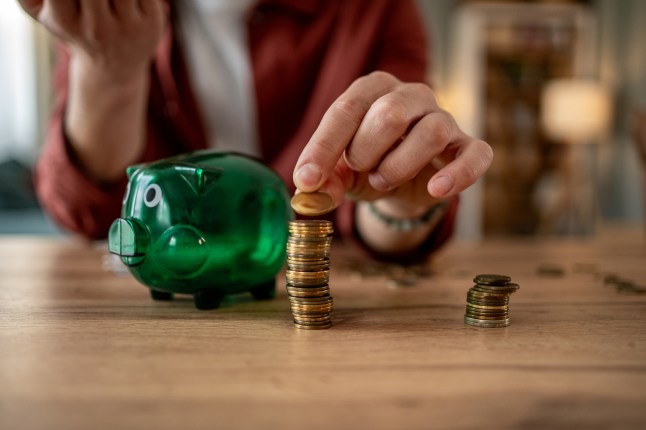 Woman stacking coins on a table with piggy bank nearby, saving money concept