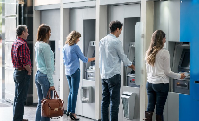 People in a line at an ATM machine.