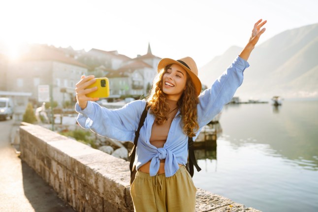 Happy tourist walks the streets and takes selfie using smartphone camera. Lifestyle, adventure, nature, active life.; Shutterstock ID 2442004001; purchase_order: -; job: -; client: -; other: -