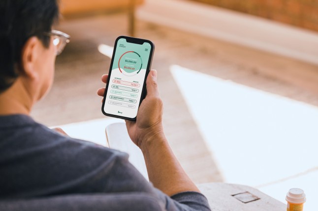 A senior man uses a banking app on his smartphone to check his bank balance.