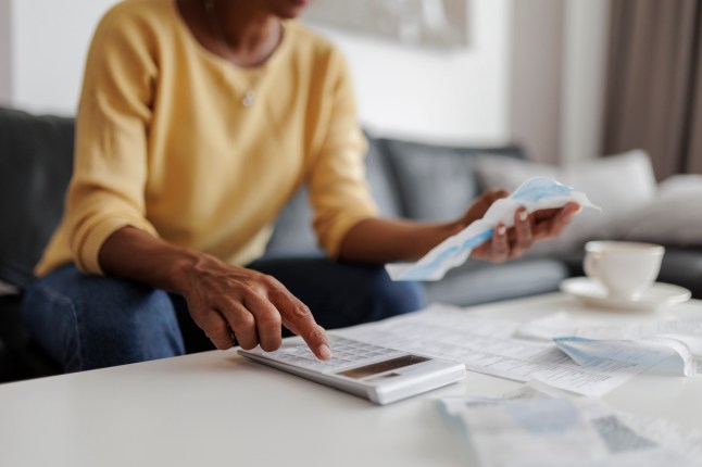 Woman looks at bills with calculator